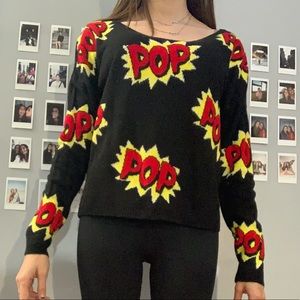 Black sweater with pow written in red and yellows